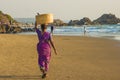 GOA, INDIA - MARCH 4: Woman in saris with basket on her head walks by Vagator beach on March 4, 2017 in Goa, India