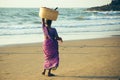 GOA, INDIA - MARCH 4: Woman in saris with basket on her head walks by Vagator beach on March 4, 2017 in Goa, India