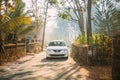 Goa, India. White Suzuki Baleno Car Moving On Country Road Through An Indian Village.