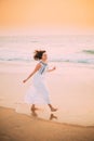 Goa, India. Young Caucasian Woman With Fluttering Hair In Wind In White Dress Walking Along Seashore, Enjoying Life And Royalty Free Stock Photo