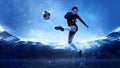 Energetic female soccer or football player in sportwear kicking ball in jump at evening stadium background. Concept of