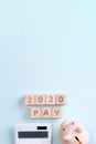 2020 goal, finance plan abstract design concept, wood blocks on blue table background with piggy bank and calculator, top view, Royalty Free Stock Photo