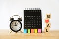 Goal metaphor word on wood block , black analog alarm clock and calendar on wooden desk for target, goal, aiming concept Royalty Free Stock Photo