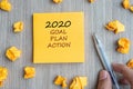 2020 Goal, Plan, Action word on yellow note with Businessman holding pen and crumbled paper on wooden table background. New Year Royalty Free Stock Photo