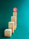 Goal and success. Arrow dart on 3d target icon on top of wooden cube blocks, bar graph steps, vertical. Royalty Free Stock Photo