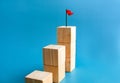 Goal and success. Red flag on the top of wooden cube blocks stacked, bar graph steps.