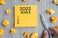 2022 Goal word on yellow note with Businessman holding pen and crumbled paper on wooden table background. New Year New Start, Royalty Free Stock Photo