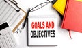 GOALS AND OBJECTIVES text on notebook with clipboard and calculator on white background