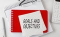 GOALS AND OBJECTIVES word on sticker on notepad with pen and calculator