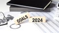 GOALS 2024 - text on a wooden block with chart and notebook