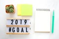 2019 goals on wood box and blank notebook paper on white marble