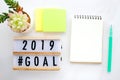 2019 goals on wood box and blank notebook paper on white marble