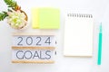 2024 goals on wood box and blank notebook paper on white marble background, business new year aim to success Royalty Free Stock Photo