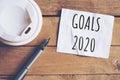 Goals for 2020 word on paper with pen and coffee cup on wooden table. Business concept Royalty Free Stock Photo