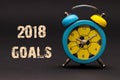 2018 goals written with alarm clock on black paper background