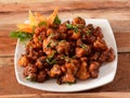 Gobi Manchurian, Popular indo-chinese food made of cauliflower florets, served in a white plate over a rustic wooden table. Royalty Free Stock Photo