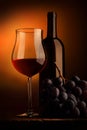 Goblet of red wine with bottle and bunch of grapes Royalty Free Stock Photo