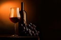 Goblet of red wine with bottle and bunch of grapes Royalty Free Stock Photo