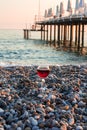Goblet with red wine isolated on sea beach in time of beautiful sunset on seascape Royalty Free Stock Photo