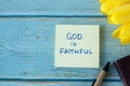 God is Faithful, handwritten quote on note with pen and tulips on wooden table Royalty Free Stock Photo