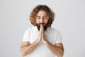 God has answers. Portrait of calm and focused eastern man with curly hair and beard holding hands in pray near mouth