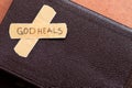 God heals, a handwritten message text on a bandage tape with closed Holy Bible Book with copy space