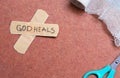 God heals a handwritten text note on a bandage tape with a medical bandage and scissors on a textured background