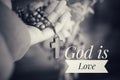 God is Love. Hand holding Rosary in black and white background. Senior woman holding rosary with open hand with Jesus Christ Cross