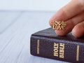 God is love, text quote with golden letter in human`s hand over closed Holy Bible Book