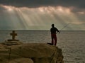 Gods rays, cross and fisherman Royalty Free Stock Photo