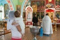 Godmother with goddaughter have ceremony of the Baptism of baby in the Orthodox church. People stand close to the baptistery. It