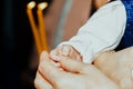 The godmother rubs the child`s hand and holds candles