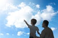 Godparent with child pointing at blue sky with white clouds