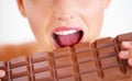 Going in for a bite.... Cropped view of a young woman biting into a big slab of chocolate. Royalty Free Stock Photo