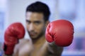 Going for the jugular. a young man wearing his boxing gloves while doing his routine at the gym.