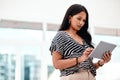 Going over her notes for the meeting. an attractive young businesswoman using a tablet while standing in her office. Royalty Free Stock Photo