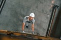 Going up on the ladder, top view. Young factory worker in grey uniform