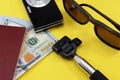 Going on vacation, money camera and sunglasses on a yellow background close-up