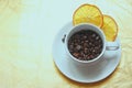 On a gold background, one white classic Cup filled with roasted coffee beans with two slices of dried orange on a saucer Royalty Free Stock Photo