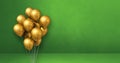 Gold balloons bunch on a green wall background. Horizontal banner Royalty Free Stock Photo