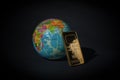 A gold bar and a globe on a black background. The concept of world wealth