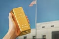 gold bar in the hand of a man against the background of the gold vault of America