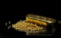 Gold bar on a pile of gold granules.