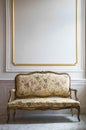 Gold baroque style sofa with floral design. White wall with gold accents. Royalty Free Stock Photo