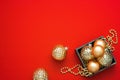 Gold baubles in different shapes and beads in the wooden box on the red background with copy space. Royalty Free Stock Photo