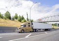 Gold big rig semi truck with grille guard transporting cargo in refrigerator semi trailer driving on the highway with road Royalty Free Stock Photo