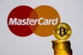 Gold Bitcoin coins with the MasterCard logo on background