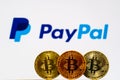 Gold Bitcoin coins with the PayPal logo on background screen.