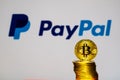 Gold Bitcoin coins with the PayPal logo on background screen.