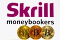 Gold Bitcoin coins with the Skrill logo on background screen.